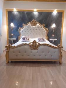 Cette chambre comprend un grand lit avec un cadre en or. dans l'établissement Mare Nostrum luxury suite, à Mazzeo