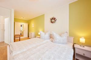 1 dormitorio con cama blanca y paredes amarillas en Ferienwohnung im Sonnenhof en Reichenberg