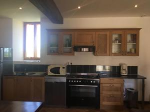 a kitchen with wooden cabinets and a black stove top oven at Gite a la ferme in Rouessé-Vassé