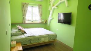 ein kleines grünes Schlafzimmer mit einem Bett und einem Fenster in der Unterkunft ELLIE HOUSE in Xiaoliuqiu