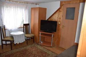 uma sala de estar com uma televisão e uma mesa e cadeiras em Domek Jaskółka em Białowieża