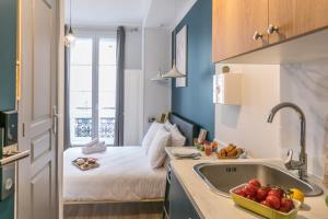 Apartments WS Louvre - Richelieu في باريس: مطبخ مع مغسلة وسرير في غرفة