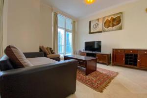 a living room with a couch and a table and a tv at Stunning 2BR - Dorra Bay Marina - Large Balcony in Dubai