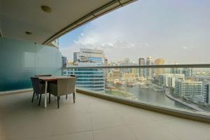 a room with a table and chairs and a large window at Stunning 2BR - Dorra Bay Marina - Large Balcony in Dubai