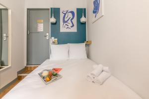 ein weißes Bett mit einem Tablett mit Essen drauf. in der Unterkunft Apartments WS Louvre - Richelieu in Paris