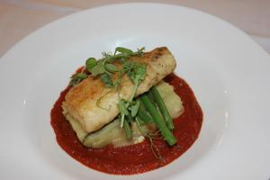 a plate of food with a piece of fish and sauce at The Windmill Inn in Watchet
