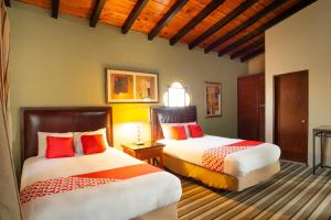 a bedroom with two beds with red pillows at OYO Hotel Hacienda Don Luis, Rosarito in Rosarito