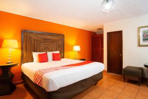 a bedroom with a large bed with orange walls at OYO Hotel Hacienda Don Luis, Rosarito in Rosarito