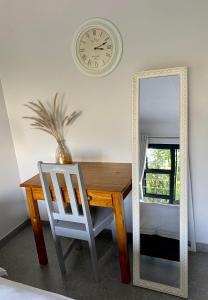 a table and a mirror with a chair and a clock at Tidor Garden Cottage in Bloemfontein