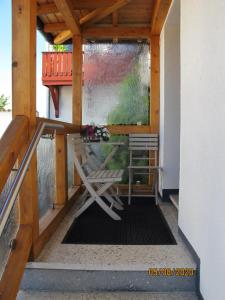 une terrasse couverte avec un banc et une chaise. dans l'établissement Gästezimmer 1 mit Bad, à Angersbach