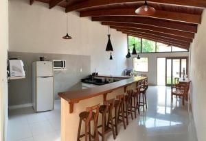 a kitchen with a bar with chairs and a refrigerator at Casarão Pireneus in Pirenópolis