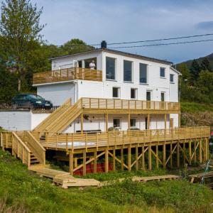 una casa su una terrazza di legno con un uomo sul balcone di Waterfront Senja a Torsken