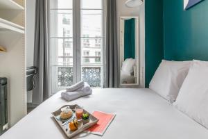 Apartments WS Louvre - Richelieu في باريس: غرفة في الفندق مع سرير عليه صينية طعام