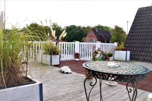 patio ze stołem, roślinami i ogrodzeniem w obiekcie Pension Zur Brandung w Büsum