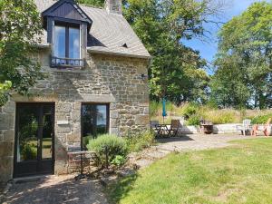 a stone house with a table and chairs in a yard at Le Grand Domaine du Rocher in Bonnemain