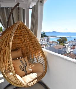 a hanging rattan chair on a balcony with a view at Angelos Design Suites in Patitiri