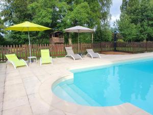 a pool with two chairs and two umbrellas at LA ROCQUE in Bonnemain