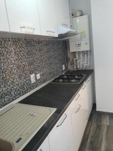 una cucina con mobili bianchi e un forno a piano cottura di Garsoniera Argedava a Bucarest Altre 37 foto