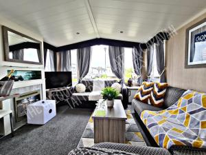 ein Wohnzimmer mit einem Sofa und einem TV in der Unterkunft Tattershall Luxury Hot Tub Caravan in Tattershall