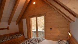 een zolderkamer met 2 bedden en een raam bij Chalet Corone Monte Zoncolan in Sùtrio