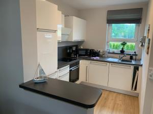 a kitchen with white cabinets and a black counter top at Ferienwohnung im Ferienhaus "Seestern" in Mücheln