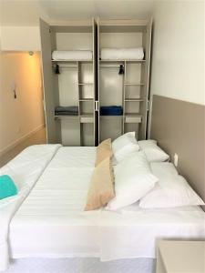 1 dormitorio con 1 cama blanca grande con almohadas blancas en Apartamento impecável FM - RETIRADA DAS CHAVES MEDIANTE AGENDAMENTO COM UMA HORA DE ANTECEDÊNCIA COM ANDREIA OU LUIS en Porto Alegre