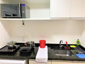 a kitchen counter with a sink and a microwave at Apartamento impecável FM - RETIRADA DAS CHAVES MEDIANTE AGENDAMENTO COM UMA HORA DE ANTECEDÊNCIA COM ANDREIA OU LUIS in Porto Alegre