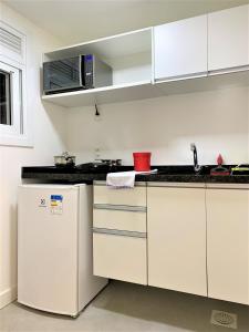 a white kitchen with a sink and a refrigerator at Apartamento impecável FM - RETIRADA DAS CHAVES MEDIANTE AGENDAMENTO COM UMA HORA DE ANTECEDÊNCIA COM ANDREIA OU LUIS in Porto Alegre