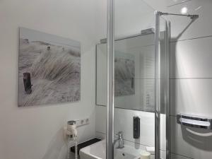 a white bathroom with a shower and a sink at Boutique Hotel Rose in Baden-Baden