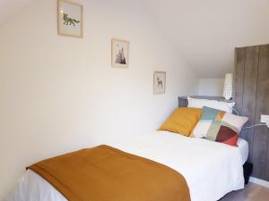 Schlafzimmer mit einem Bett mit weißer Bettwäsche und bunten Kissen in der Unterkunft Gîte de Beg Menez Le 26 - Gîte à La Forêt-Fouesnant in La Forêt-Fouesnant