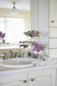 a bathroom sink with purple flowers in vases on it at The Empty Nest B & B in Carrying Place