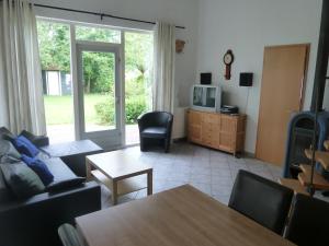 ein Wohnzimmer mit einem Sofa, einem TV und einem Tisch in der Unterkunft Ferienhaus Lisakowski in Warmenhuizen