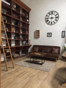 a living room with a couch and a clock on the wall at Entre Loire et Sologne Maison d'hôtes in Saint-Gervais-la-Forêt