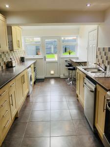 a large kitchen with white cabinets and a tile floor at Furzy House in Pembrokeshire