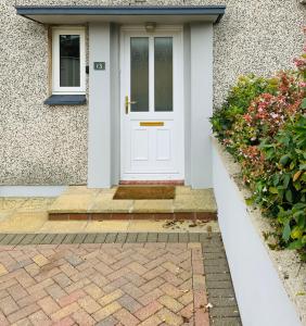 uma porta branca da frente de uma casa com flores em Furzy House em Pembrokeshire