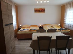 エプリーニにあるTündér Szállóのベッド2台、テーブル、椅子が備わる客室です。