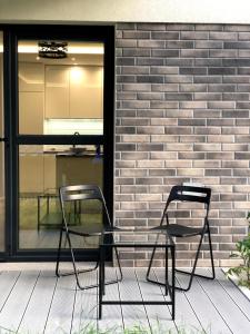 twee stoelen op een veranda naast een stenen muur bij Downtown Apartment in Toruń