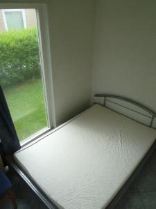 um pequeno quarto com uma cama ao lado de uma janela em Ferienhaus Lisakowski em Warmenhuizen