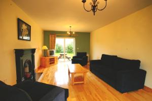 a living room with a black couch and a fireplace at Doonbeg Holiday Homes in Doonbeg