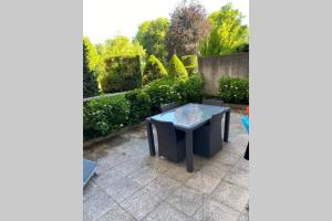 a patio with a table and some bushes at LE PORTE VERRIER - MEUBLE CLASSE 3étoiles - Hypercentre - Terrasse 30M2, Vue Parc in Vichy