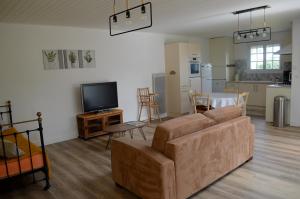een woonkamer met een bank en een tv en een keuken bij Maison de caractère proche des Sables d’Olonne in Talmont