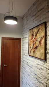 a painting hanging on a brick wall next to a door at Old Kaunas Apartment in Kaunas