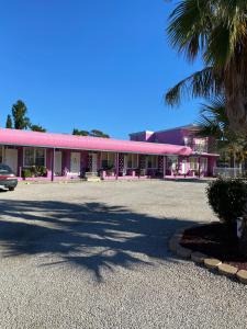 un estacionamiento frente a un edificio rosa en Paddle Steamer Motel, en Swan Hill