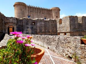 a castle with a wall and flowers in front of it at Appartamento per Turisti Mesovia in Santa Severina