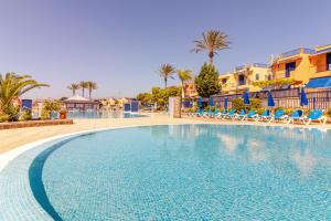 una piscina in un resort con sedie e palme di Bahia Meloneras a San Bartolomé