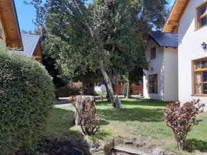 a house with a tree in the yard at Apart Hotel Bungalows El Viejo Cipres in San Carlos de Bariloche
