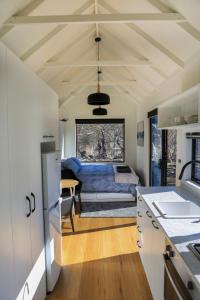 a kitchen and living room with a bed in a room at Big Yard Escapes - Two Off-Grid Tiny Houses on the Mowamba River in Jindabyne