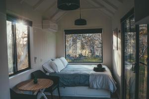 a small bedroom with a bed and a window at Big Yard Escapes - Two Off-Grid Tiny Houses on the Mowamba River in Jindabyne