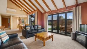a living room with a couch and a tv and a table at Heritage Village - Villa #5 in Wanaka