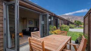 - une terrasse avec une moustiquaire, une table et des chaises en bois dans l'établissement Heritage Village - Villa #5, à Wanaka